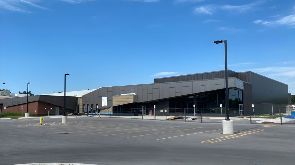 Das moderne Gebäude der Great Lakes District Secondary School mit Glasfassade steht vor einem gepflasterten Parkplatz.