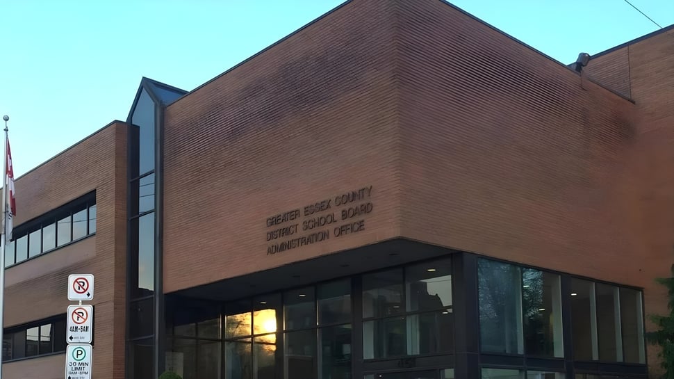 Das große Backsteingebäude mit Glasfenstern des Greater Essex County District School Board vor klarem blauem Himmel.