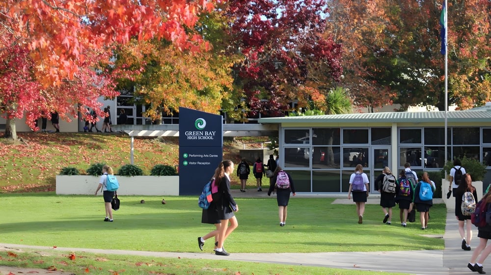 Schüler der Green Bay High School laufen und versammeln sich auf dem Campus bei herbstlich farbigen Bäumen.