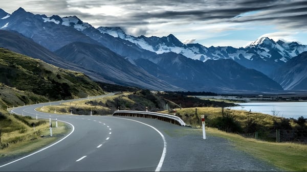 Eine Straße führt durch eine bergige Landschaft mit schneebedeckten Gipfeln im Hintergrund auf dem Gelände der Green Bay High School.
