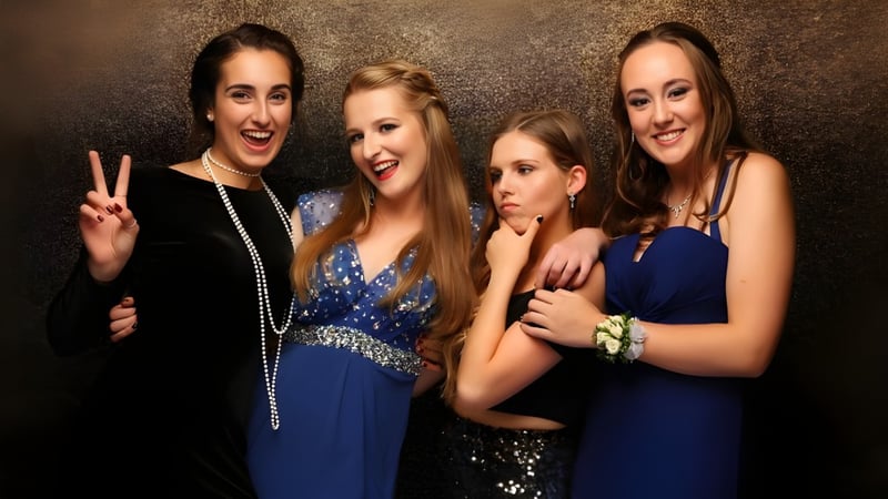 Vier Schülerinnen der Green Bay High School posieren in formeller Kleidung vor dunklem Hintergrund, eine zeigt das Peace-Zeichen.