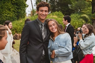 Ein junges Paar steht zusammen und lächelt in einem grünen Außenbereich auf dem Campus des Greene's College Oxford.