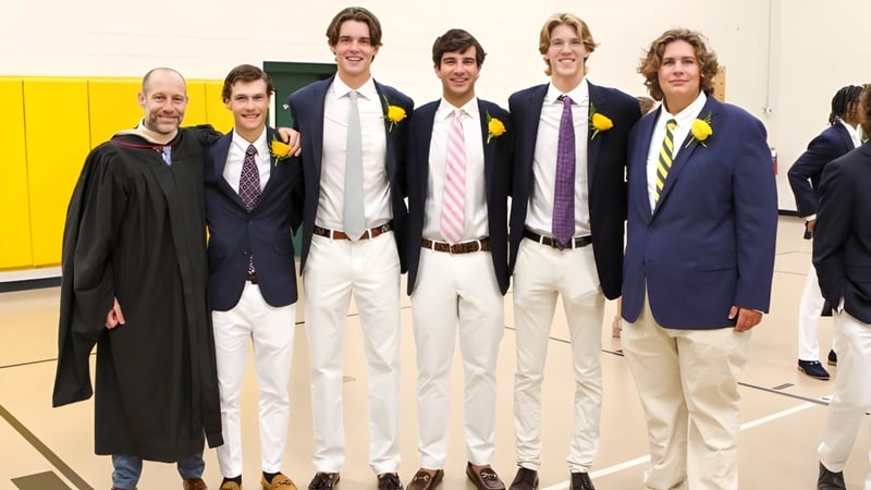 Eine Gruppe junger Schüler der Greensboro Day School steht in formeller Kleidung vor einer gelben Wand in der Schule.