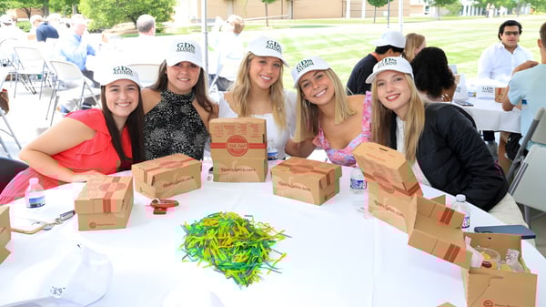 Eine Gruppe von Schülerinnen der Greensboro Day School steht im Freien um einen Tisch und hält Kartons in der Hand.