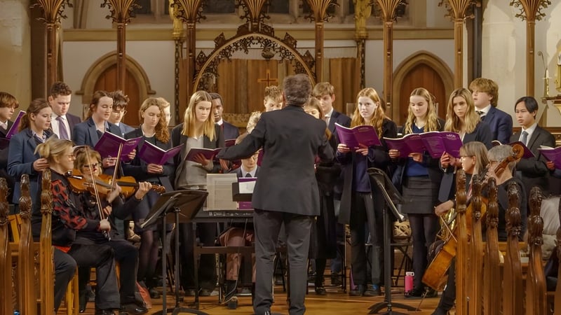 Ein Chor in lila Roben singt auf der Bühne in einer prunkvollen Kathedrale auf dem Campus der Gresham’s School.