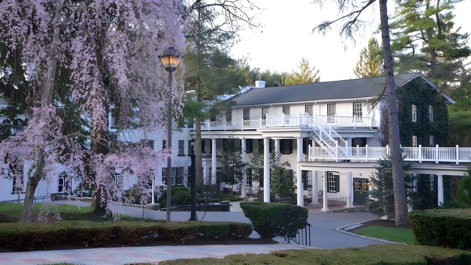 Das historische Gebäude der Grier School ist von grünen Bäumen und blühender Vegetation umgeben.
