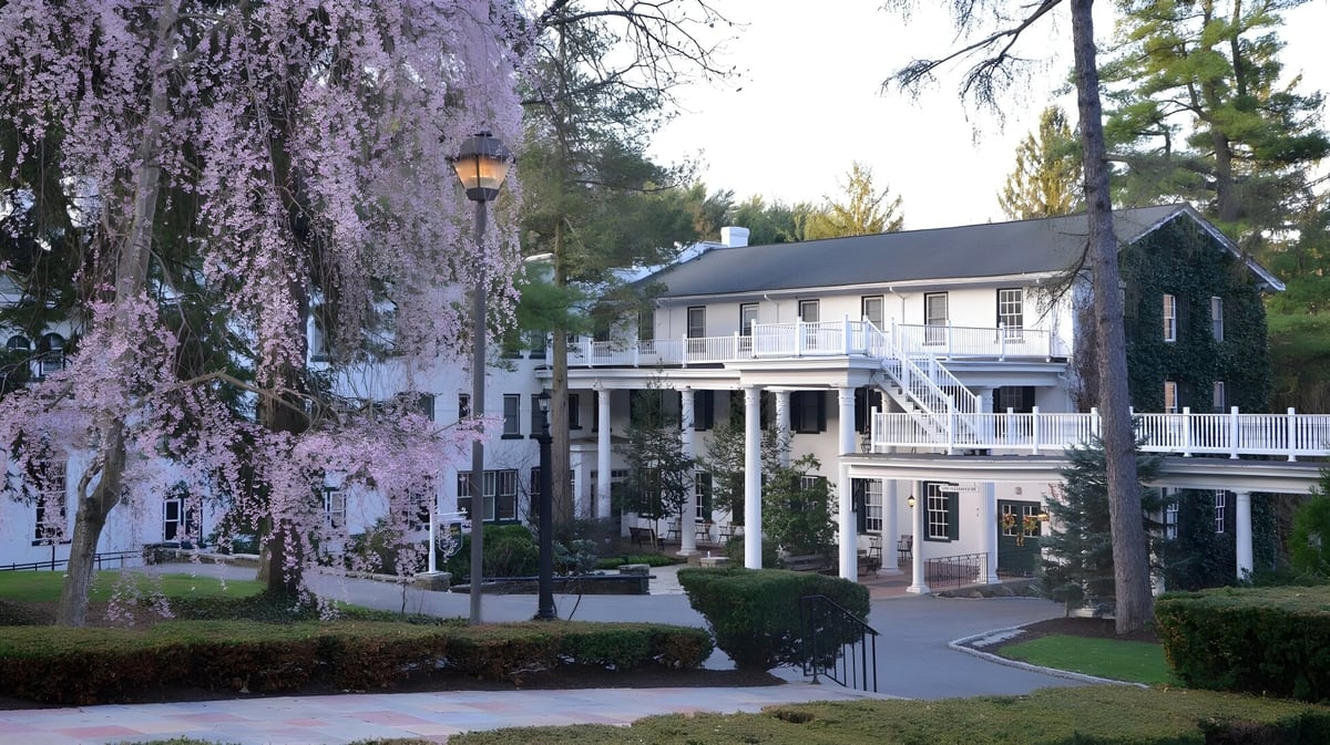 Das historische Gebäude der Grier School ist von grünen Bäumen und blühender Vegetation umgeben.