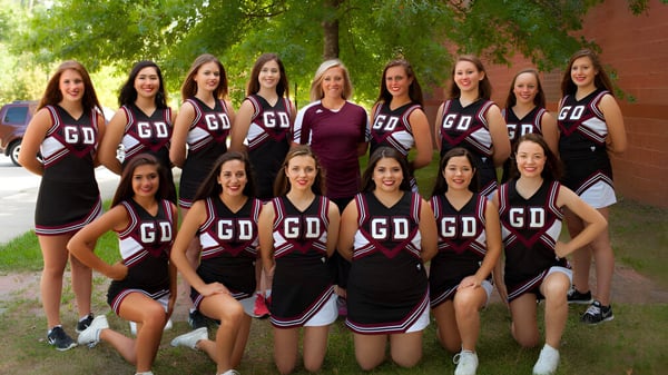 Eine Gruppe von Schülerinnen der Groton-Dunstable Regional High School steht gemeinsam im grünen Freien mit Bäumen im Hintergrund.