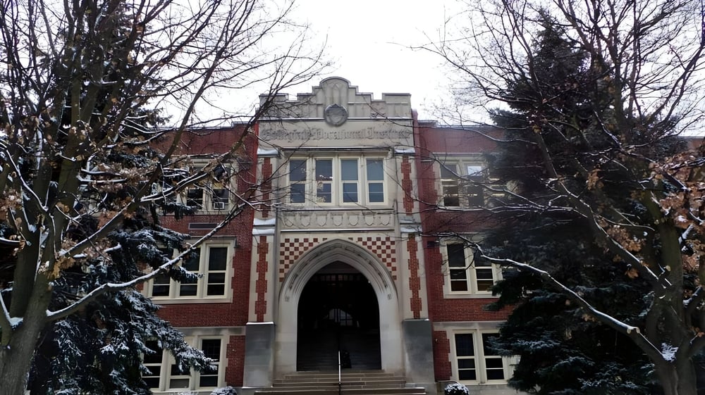 Das historische Hauptgebäude des Guelph Collegiate Vocational Institute steht im verschneiten Wald.