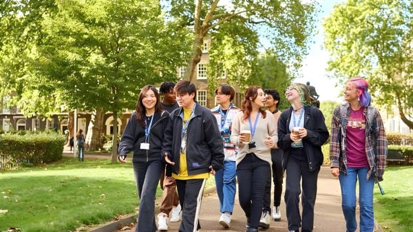 Eine Gruppe Schülerinnen und Schüler geht gemeinsam auf einem Weg im grünen Campus der Guildhouse School London.