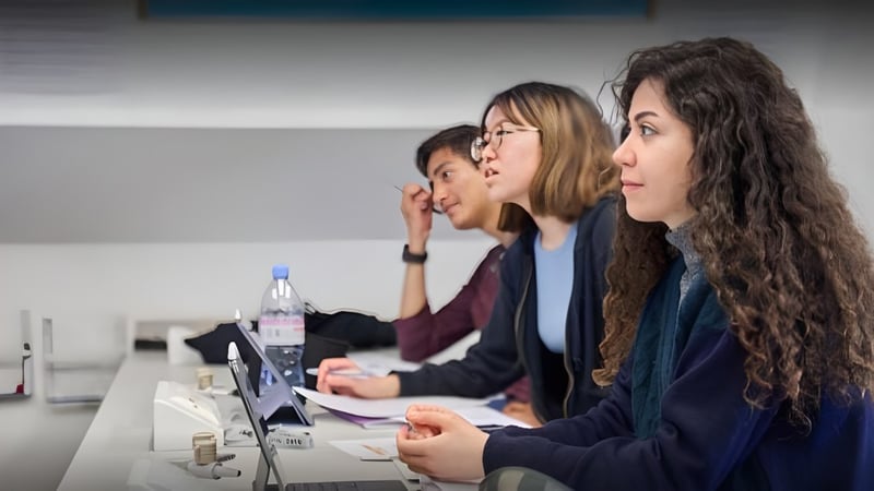 Schüler der Guildhouse School London sitzen an einem Tisch und arbeiten gemeinsam im Klassenraum.