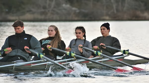 Vier Schülerinnen und Schüler der Gulf Islands Secondary School rudern auf einem See umgeben von Wald.