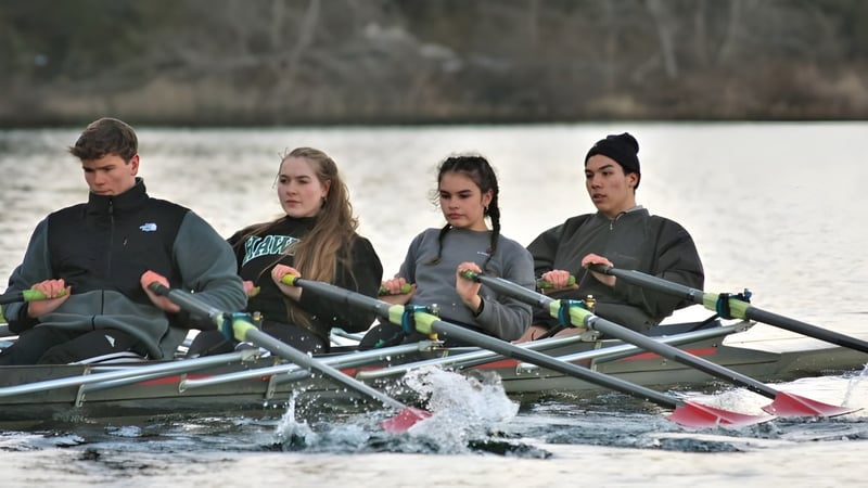 Vier Schülerinnen und Schüler der Gulf Islands Secondary School rudern auf einem See umgeben von Wald.