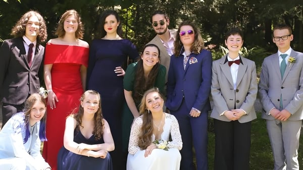 Eine Gruppe Schüler der Gulf Islands Secondary School posiert in formeller Kleidung im Freien vor Bäumen und Grün.