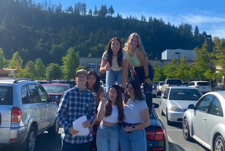 Eine Gruppe von Schülern steht auf dem Schulgelände der G.W. Graham Secondary School vor Bergen und Bäumen.