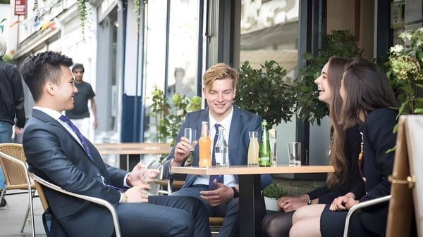 Eine Gruppe gut gekleideter Personen unterhält sich an einem Außen-Café auf dem Gelände der Haberdashers' Monmouth Schools.