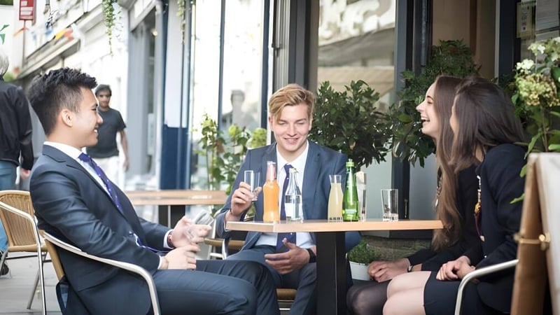 Eine Gruppe gut gekleideter Personen unterhält sich an einem Außen-Café auf dem Gelände der Haberdashers' Monmouth Schools.