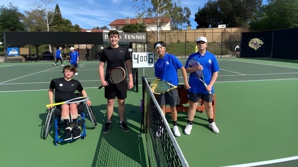 Schüler der Hackett High School stehen auf dem Tennisplatz vor dem Netz bei einer Trainingseinheit im Freien.