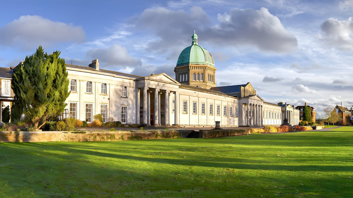 Gebäude mit Kuppel und grünem Dach auf dem Campus der Haileybury School vor einer grünen Wiese.