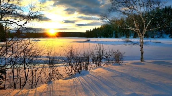 Eine verschneite Winterlandschaft mit zugefrorenem See und Sonnenuntergang nahe der Haliburton Highlands School.