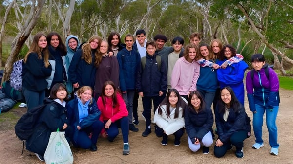Eine Gruppe Schüler der Hallett Cove School steht in einem bewaldeten Gebiet mit hohen Bäumen und dichter Vegetation.