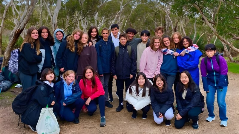 Eine Gruppe Schüler der Hallett Cove School steht in einem bewaldeten Gebiet mit hohen Bäumen und dichter Vegetation.