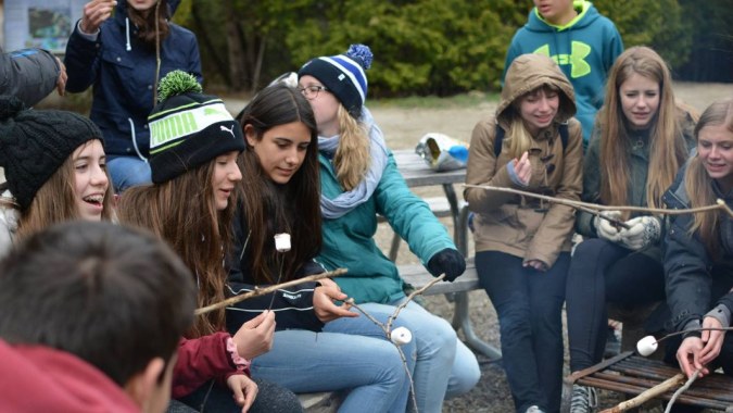 Eine Gruppe von Schülerinnen und Schülern der Hamelin-Laie International School steht draußen bei einer Aktivität und unterhält sich.