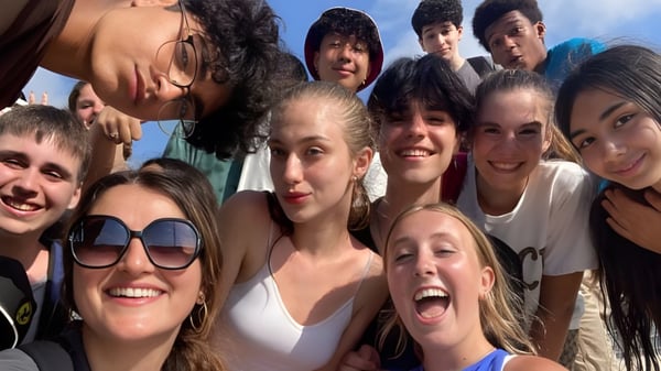 Eine Gruppe lachender Schülerinnen und Schüler der Hamelin-Laie International School versammelt sich im Freien unter blauem Himmel.