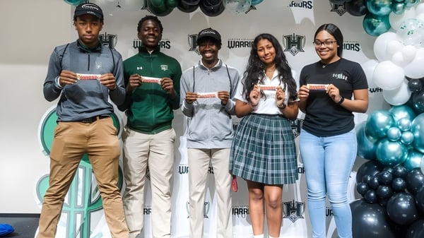 Schüler der Hamilton Christian Academy stehen vor einer Wand mit sportlichen Bildern.