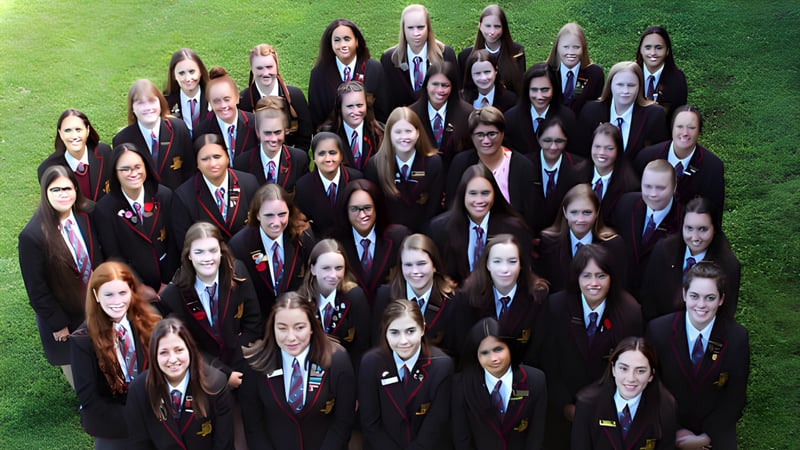 Eine Gruppe Schülerinnen der Hamilton Girl's High School steht gemeinsam auf einem grasbewachsenen Feld.