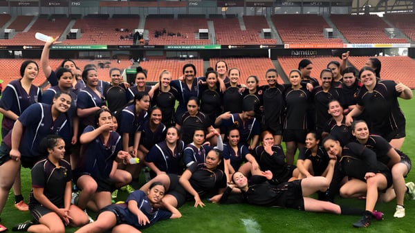 Eine große Gruppe Schülerinnen der Hamilton Girl's High School posiert auf dem Sportfeld vor dem Stadion.
