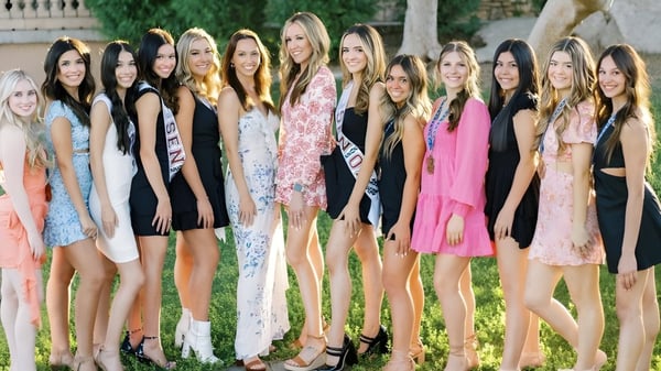 Eine Gruppe junger Frauen in bunten Kleidern posiert im Grünen auf dem Gelände der Hamilton High School.