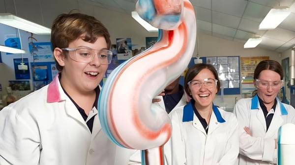 Drei Personen in weißen Laborkitteln mit einem großen bunten Herzmodell im Unterricht am Hamilton Secondary College.