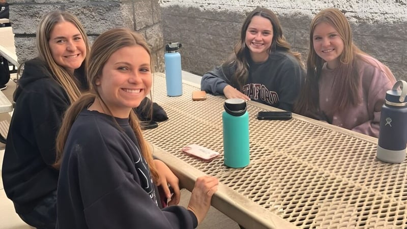 Vier Schülerinnen der Hamilton High School posieren gemeinsam im Außenbereich vor einer Betonwand.