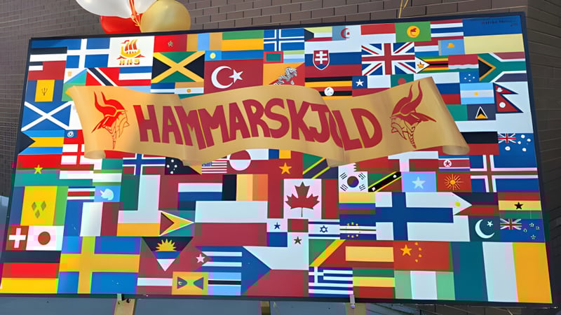 Ein großes Banner mit dem Schriftzug Hammarskjold High School umgeben von einer Collage aus verschiedenen Nationalflaggen.