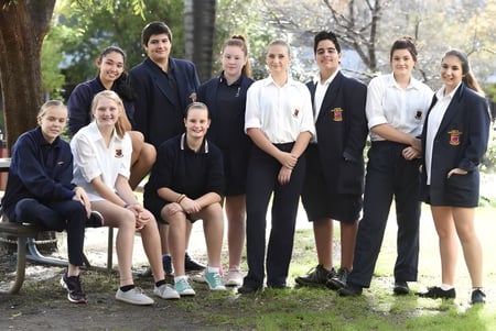 Eine Gruppe von Schülerinnen und Schülern steht und sitzt gemeinsam in einem natürlichen Außenbereich der Hampton Senior High School.