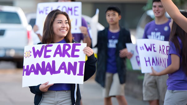 Eine Gruppe von Schülerinnen und Schülern hält in der Schule Hanalani Schools Schilder mit der Aufschrift We are Hanalani.