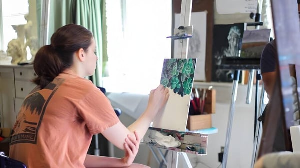 Eine Schülerin der Hanham Woods Academy steht in einem Raum und malt auf einer Staffelei.