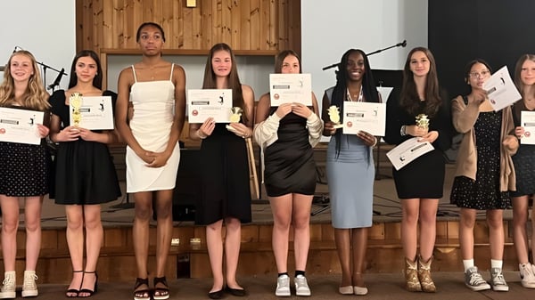 Eine Gruppe Schülerinnen der Harmony Christian School hält in einem Holzraum jeweils eine Urkunde in der Hand.