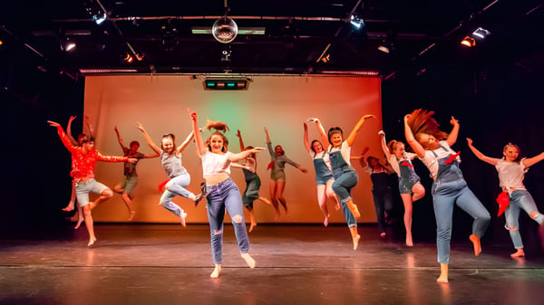 Schüler des Havant College führen auf einer Bühne mit buntem Licht eine dynamische Tanzaufführung auf.