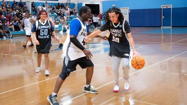 Zwei Basketballspieler der Hawai'i Pacific University dribbeln auf dem Spielfeld vor Zuschauern.