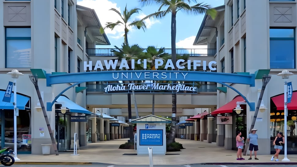 Der Eingang der Hawai'i Pacific University mit einem großen Schild und Palmen vor dem Aloha Tower Marketplace.