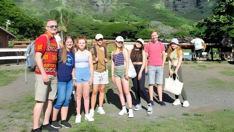 Eine Gruppe von Schülerinnen und Schülern steht gemeinsam in einem grünen Außenbereich auf dem Campus der Hawai'i Pacific University.