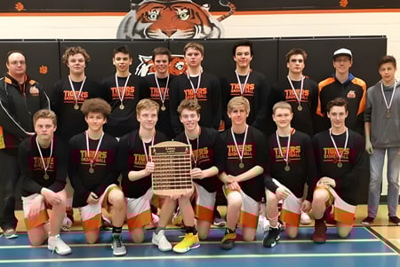 Eine Gruppe junger Basketballspielerinnen und Spieler posiert vor dem Tiger-Maskottchen an der Wand der Hay Lakes School.