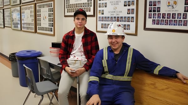 Zwei Personen stehen in einer Werkstatt auf dem Campus der Hay Lakes School vor einer Wand mit gerahmten Bildern.