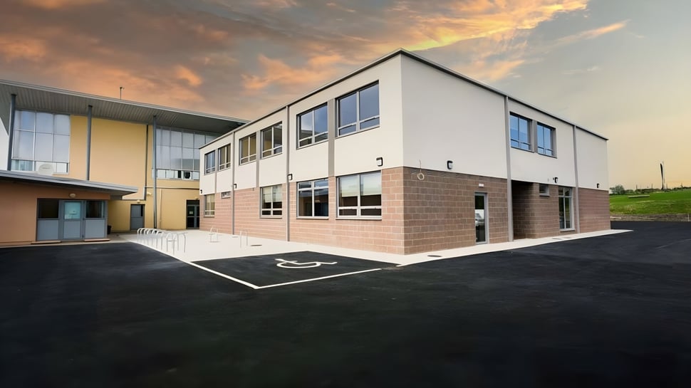 Das moderne zweistöckige Gebäude des Hazelwood College steht vor einem farbenfrohen Sonnenuntergang.