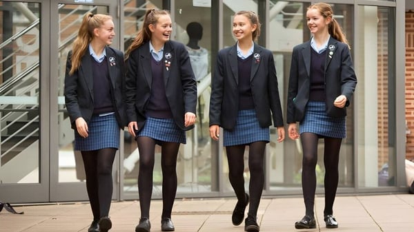 Vier Schülerinnen der Headington School stehen zusammen und lächeln vor einem Glasgebäude.