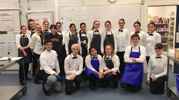 Schüler der Heathfield High School stehen in der Schulküche in Kochuniformen zusammen.