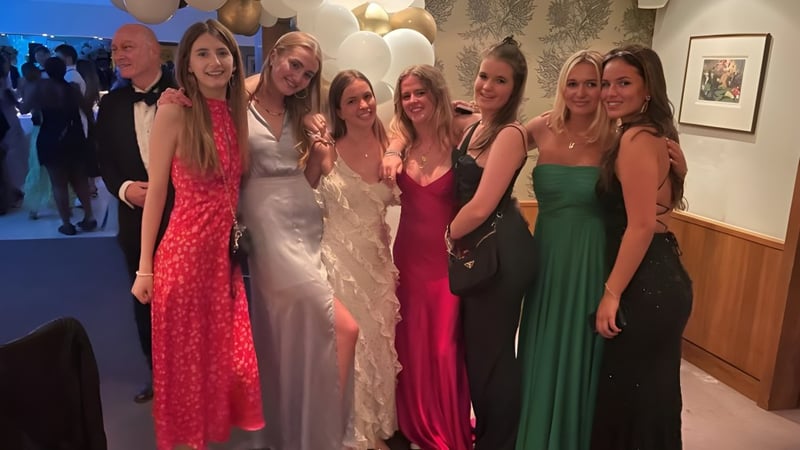 Eine Gruppe junger Schülerinnen der Heathfield School in festlicher Kleidung posiert gemeinsam vor Dekorationen.