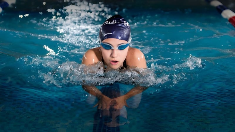 Ein Schwimmer mit Schwimmbrille und Badekappe steigt aus dem Wasser des Pools auf dem Gelände der Heathfield School in Ascot.